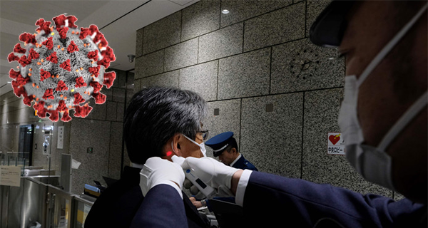 Een veiligheidsmedewerker meet de temperatuur van een bezoeker in een overheidsgebouw in Tokio ©AFP